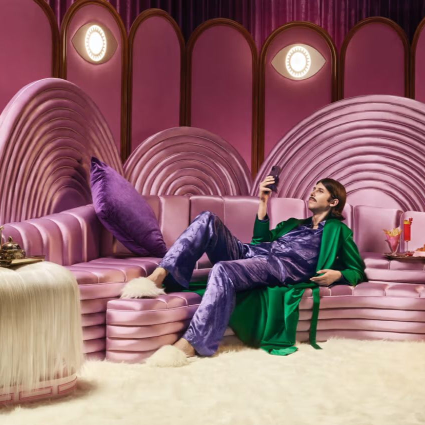 A man lying on a stylish coach looking at his phone.